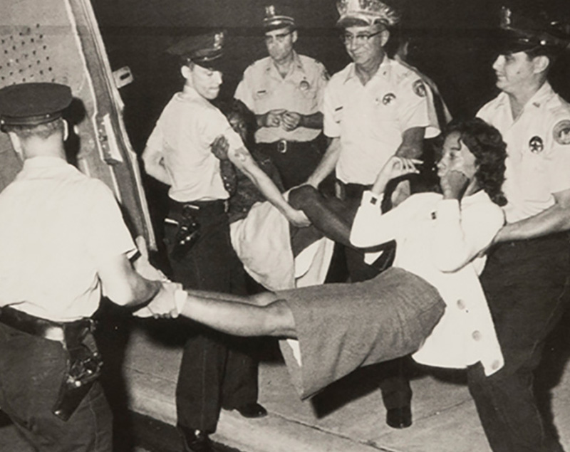 Two young black female protestors being carried away by white police