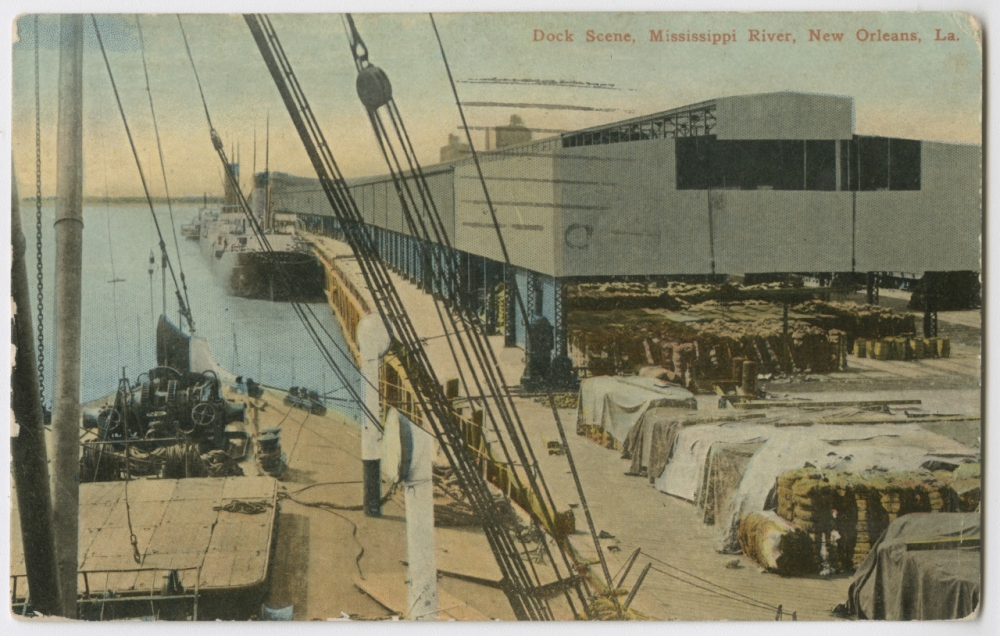 A circa 1912 postcard labeled "Dock Scene, Mississippi River, New Orleans, La." It depicts several steamships docked by a warehouse and a wharf crowded with bales of cotton and barrels.