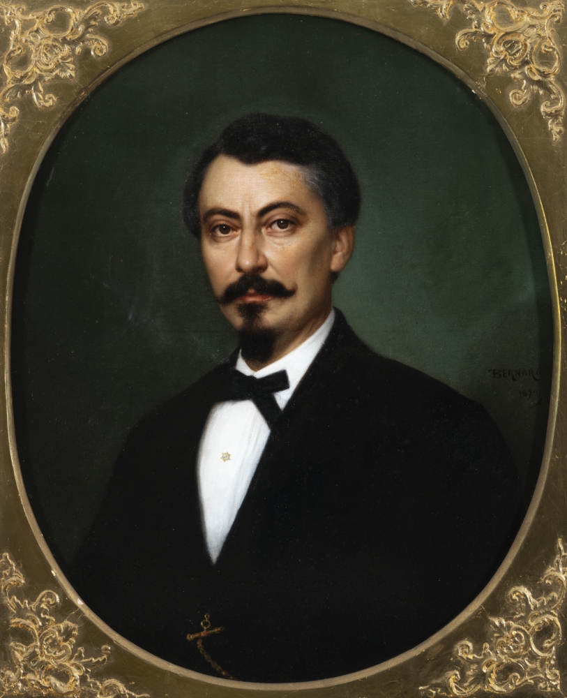 Portrait of a man with a dark goatee and dark suit.