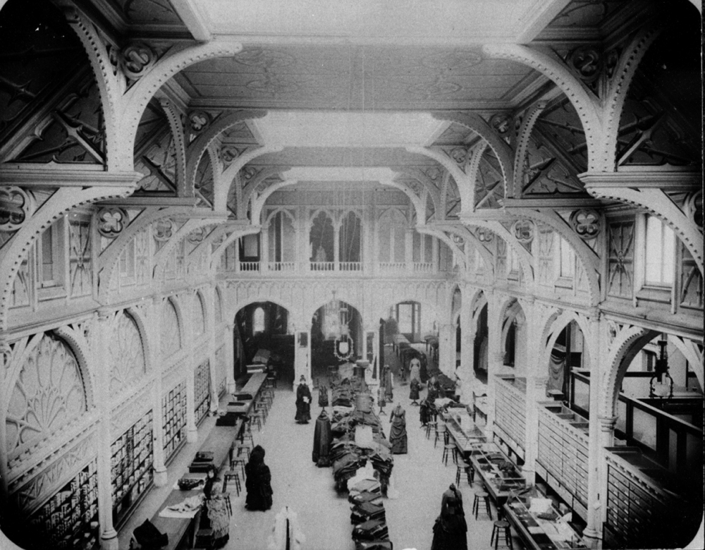 Black-and-white photo of the high-ceilinged sales floor of a department store, taken from above.