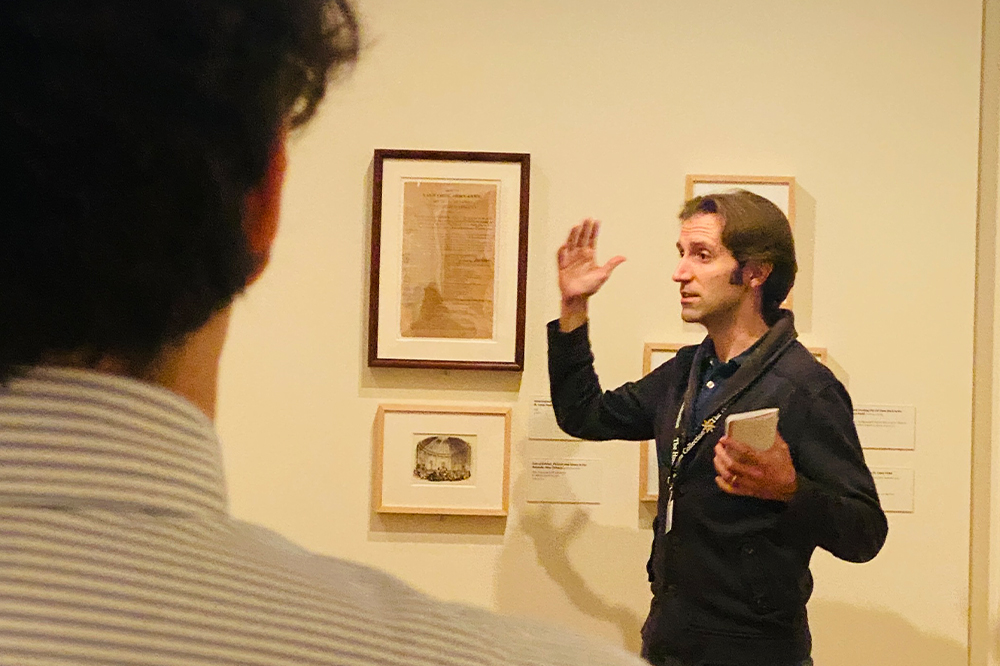 Tour guide gestures towards artifacts in THNOC's French Quarter History galleries