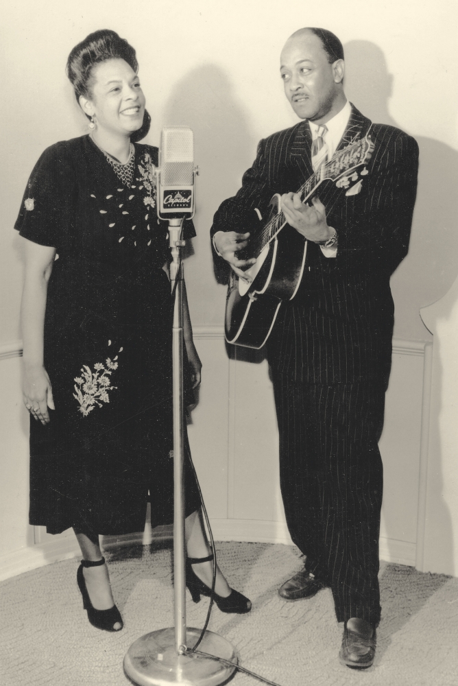 Danny and Blue Lu Barker stand in front of a microphone for a Capitol Records publicity photograph
