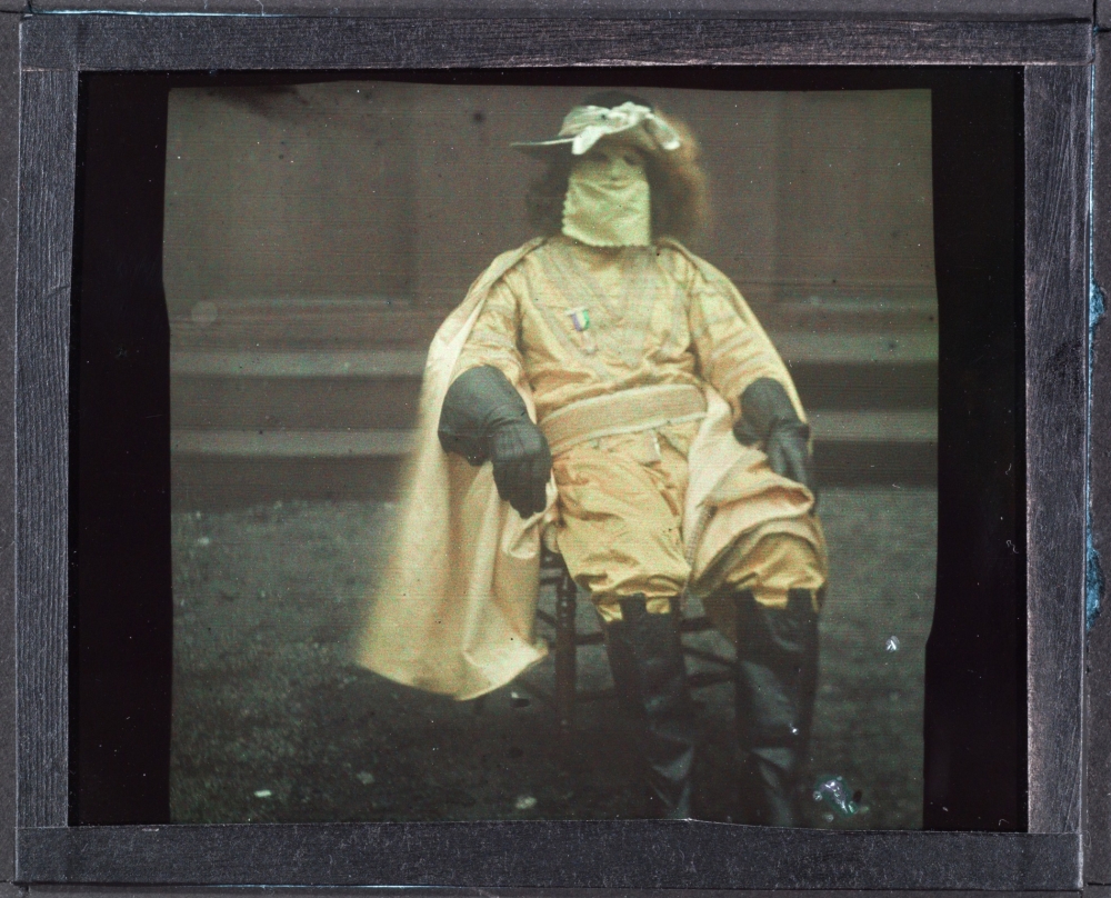 Autochrome portrait of Ernest Doty Ivy (1871 - December 26, 1928), a Lieutenant in the Krewe of Rex. He is seated and wearing a Mardi Gras costume that includes a Rex ducal decoration on a gold tunic worn with gold pants, black riding boots, long black gloves, gold cape, wig, hat, and a gold mask. 