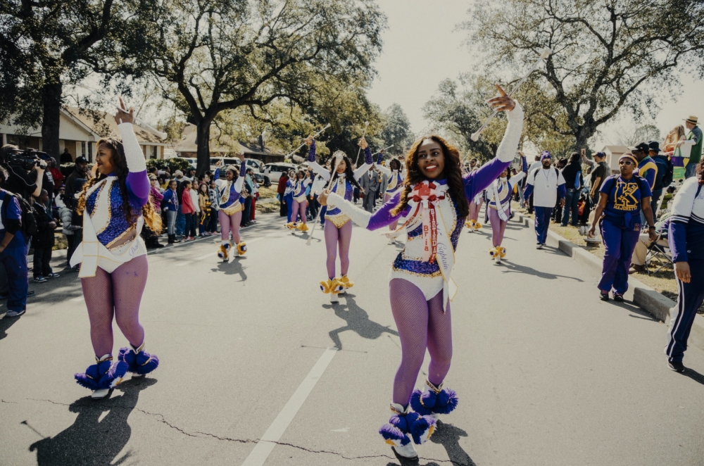 Full color photograph by Akasha Rabut showing the dance team of the Edna Karr High School band.